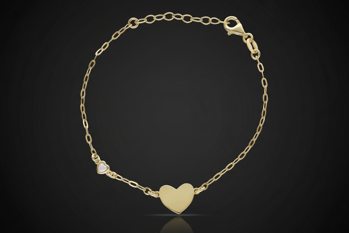 Pulsera dorada con corazón liso y circonita en forma de corazón sobre fondo negro